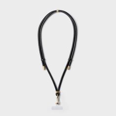 a black leather necklace with gold clasps and a white tag hanging from the end