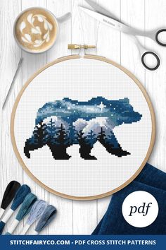 a cross stitch pattern with an image of two bears in the woods, one is blue and