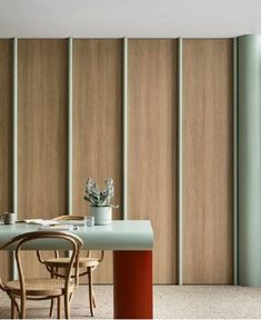 a dining room table with chairs and a potted plant next to the sliding doors