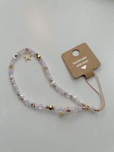 a white beaded necklace with gold stars on it and a tag attached to it