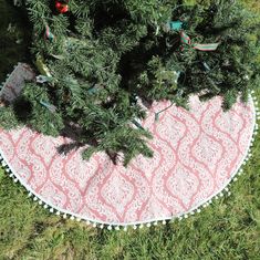 a christmas tree skirt is on the ground in the grass with ornaments hanging from it