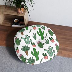 a green cactus pattern on a white round seat cushion next to a potted plant