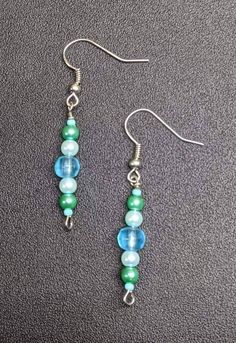 Fun and funky fierce and fabulous earrings. Blue and green glass beads. Made in Hawaii. Nickel-free Green Beaded Earrings For Parties, Trendy Blue Earrings With Dangling Beads, Trendy Green Beaded Dangle Earrings, Trendy Blue Round Bead Earrings, Trendy Green Beaded Drop Earrings, Green Czech Glass Dangle Beaded Earrings, Trendy Green Earrings With Colorful Beads, Green Czech Glass Earrings With Colorful Beads, Handmade Green Crystal Earrings With Round Beads