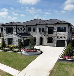 an aerial view of a large house with landscaping in the front yard and driveway leading up to it