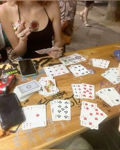 a woman sitting at a table with playing cards and cell phones on top of it