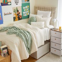 a bedroom with white bedding and posters on the wall above it's bed