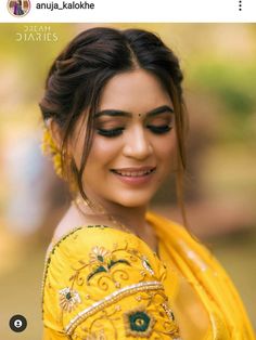 a woman in yellow sari smiling and looking at the camera with her eyes closed