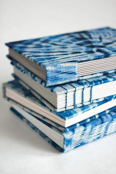 three books are stacked on top of each other, one is blue and the other is white