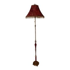 a floor lamp with a red shade on the top and chain hanging from it's side