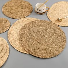 four placemats and two cups are arranged on a table with straw coasters