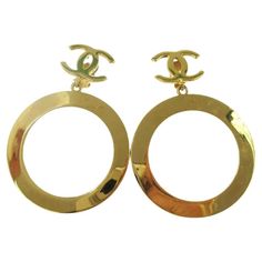 This is an authentic pair of Chanel CC hoop clip on earrings in gold tone. These chic earrings feature large gold hoops suspended from a classic CC logo. Color: Gold Material: Metal Marks: Chanel logo on backside Clasp Style: Clip on earrings Year: early 90s Measures: 2.25” x 2.25” Pendant drop: 3.25"” Condition: Very good. Faint hairline scratches. Pristine. Made in Italy Chanel Logo, Chic Earrings, Chanel Vintage, Gold Hoops, Vintage Chanel, Gold Hoop, Gold Material, Vintage Gold, Clip On Earrings