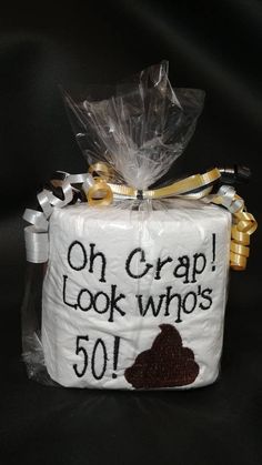 a cake wrapped in plastic and tied to a ribbon with the words on crap look who's 50