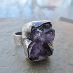 Raw Amethyst Druzy Ring Purple Rough Gemstone Crystal Rustic Silver Ring: Chunky rustic ring of natural raw Amethyst set in sterling silver. I hammered, stamped and distressed the bezel and the band for an organic look. Size is 7.5. 100% handmade by me in all sterling silver in my little home studio. Enter my shop: https://www.etsy.com/shop/artdi Join me on Facebook: https://www.facebook.com/Artdi-Diana-Anton-Jewelry-Design-44805607932/ Find me on Instagram: https://www.instagram.com/dianaantonjewelrydesign/ Elven Witch, Witch Rings, Rustic Ring, Rough Jewelry, Raw Crystal Ring, Amethyst Set, Rustic Rings, Ring Purple, Druzy Jewelry