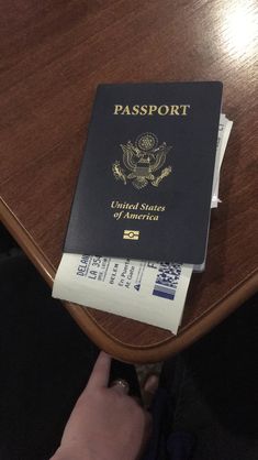 a person holding a passport on top of a wooden table