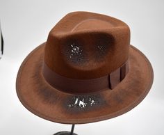 Add the finishing touches to your Dream Haunting Killer with this Brown Fedora with a burned look. Reminiscent of a horror flick and frightening slayers, this felt hat feature burned and tattered spots to give a ominous look. Each hat is hand burned for a killer look. Great for Men, Women, and teens! Strike fear and uncertainty in the others around you in your spooktacular costume. Killer costume accessory hat is measured approximately 57 cm or 7 1/8. Perfect for Cosplay, Halloween, Theatrical and more! Hat stands about 5 inches tall. Made with 100% polyester material which is like a permafelt. For Ages 14 and Older **Hats may look slightly different than the image due to handmade burns. *Handmade, assembled, and crafted by hand with assistance from hand driven fabric forming and hand driv Halloween Fedora Costume Hat, Fitted Fedora Halloween Costume Hat, Fitted Fedora Costume Hat For Halloween, Brown Halloween Costume Hat, Adjustable Short Brim Fedora For Halloween, Adjustable Short-brim Fedora For Halloween, Killer Costume, Dream Cosplay, Brown Fedora