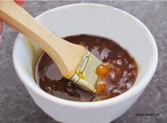 a person holding a wooden brush in a bowl filled with liquid