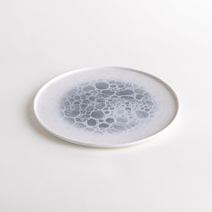 a white plate with bubbles on it sitting on top of a table next to a cup