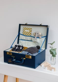 an open suitcase sitting on top of a white table next to a plant and stuffed animal