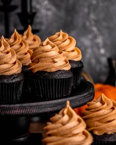 chocolate cupcakes with frosting on top and pumpkins in the background