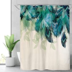 a shower curtain with blue and green feathers on it next to a potted plant