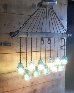 a chandelier made out of old glass bottles hanging from the side of a wooden wall