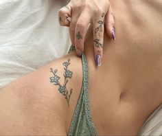 a woman with tattoos on her stomach is laying down and holding onto the side of her body