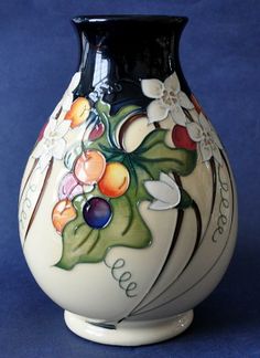 a white and black vase with flowers painted on the side, sitting on a blue background