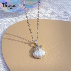 The Coastal Charm Shell Necklace is a delightful and whimsical piece of jewelry inspired by the beauty of the coast and the treasures of the sea. This necklace features real or crafted shells that evoke a sense of beachy charm and coastal allure.  - Brand: Thaya  - Material: Titanium Steel  - Size: Chain length 40+5cm  - Shape: Shell  - Gender: Women's Shell Necklace With Pearl Pendant, White Shell Charm Necklace Gift, Elegant Shell Necklace With Lobster Clasp, Ocean-inspired Shell Pendant Necklace With Lobster Clasp, Ocean-inspired Pearl Pendant Necklaces As Gifts, White Ocean-inspired Charm Necklace For Gift, Gift Ocean-inspired Shell Necklace With Starfish Charm, Shell-shaped Pearl Charm Necklace, Ocean-inspired White Charm Necklace As Gift