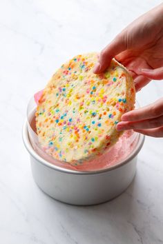 someone is dipping some kind of cake into a bowl with sprinkles on it