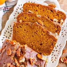 slices of pumpkin bread on a plate with pecans and oranges in the background