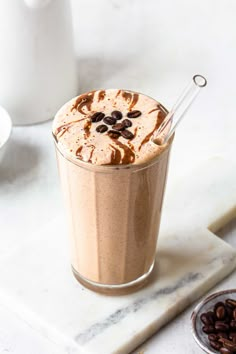 there is a drink with chocolate and coffee beans on the table next to some nuts