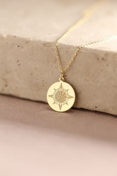 a gold necklace with a compass on it