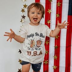 a young child is standing in front of an american flag and holding his hands out