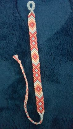 an orange and white beaded tie laying on top of a blue blanket next to a string