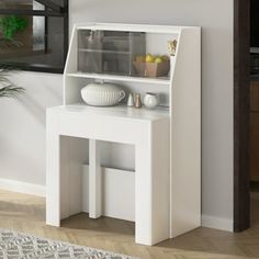 a small white table with a shelf on the top and shelves below it, in front of a window