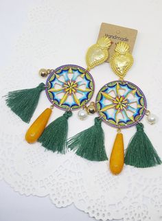 Sicilian cart wheel earrings with yellow agate pendant, green tassels, golden sacred holy heart Italian folklore, Sicily traditional The inspiration for these earrings comes from the colorful wheels of the typical traditional Sicilian carriages. This piece of jewelry composed by an appropriately shaped and painted wooden base, embellished with green cotton tassels and a central agate pendant. Golden tone studs (zinc-alloy, nickel free) are shaped as sacred hearts. Please take a look at this diff Bohemian Yellow Earrings With Latkans, Yellow Bohemian Earrings With Latkans, Traditional Gold Tassel Festival Earrings, Traditional Gold Tassel Earrings For Festivals, Yellow Bohemian Round Earrings, Bohemian Yellow Round Earrings, Bohemian Gold Tassel Earrings Gift, Gold Bohemian Tassel Earrings For Gift, Yellow Bohemian Jewelry With Latkans