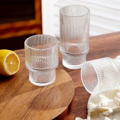 two glasses sitting on top of a wooden table next to a slice of lemon and whipped cream