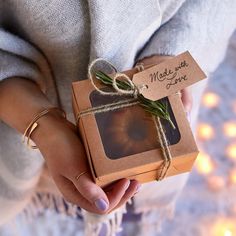 a person holding a small box with a string tied around it that says made with love