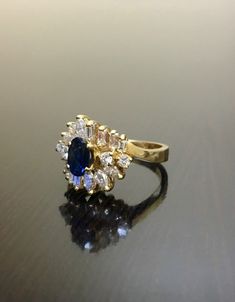 DeKara Designs Clearance Metal- 14K Yellow Gold, .583. Stones- 1 Oval Blue Sapphire 0.60 Carats, 4 Round Diamonds, 8 Square Baguette Diamonds, 6 Marquise Diamonds, G-H Color VS2-SI1 Clarity 1.10 Carats. Size- 6 1/4. FREE SIZING Handmade 14K Yellow Gold Sapphire and Diamond Ring. This ring is inspired by the Art Deco era with an enticing round fiery oval blue sapphire. The sapphire is set in between 4 prongs. The sapphire has a total of 18 round, baguette, and marquise diamonds on the top and the Sapphire Diamond Wedding Ring, Sapphire Diamond Engagement Ring, Wedding Ring Art, Art Deco Sapphire Ring, Diamond Sapphire Engagement Ring, Sapphire Diamond Engagement, Art Deco Wedding Rings, Sapphire And Diamond Ring, Blue Sapphire Diamond