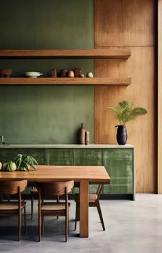 a dining room with green walls and wooden shelves on either side of the kitchen table