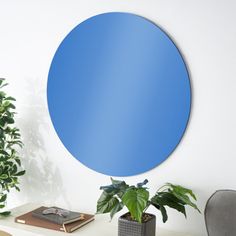 a blue circular mirror sitting on top of a white table next to a potted plant