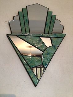 a triangle shaped mirror mounted to the side of a wall next to a light fixture