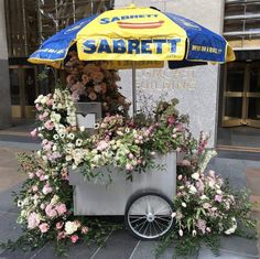 a cart with flowers and an umbrella on the street