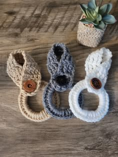 three crocheted baby booties with wooden buttons on the bottom and one has a button in the middle