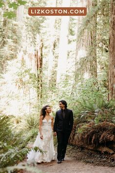 a bride and groom walking through the woods together