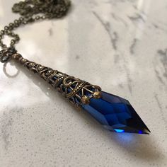 This beautiful necklace is made with a genuine marked Swarovski Pendulum Cobalt Blue crystal.  The crystal is 40 mm long and with the antique brass filigree it is 50 mm in length.  You can choose what length you want the antique brass chain for this beautiful crystal pendant to dangle from.  The necklace comes in a black jewelry box, so its ready to wrap  if this is to be a gift.  The necklace will be sent USPS first class mail. Atlantis Jewelry, Icicle Necklace, Xoxo Necklace, Clear Crystal Necklace, Pink Statement Necklace, October Birthstone Jewelry, Victorian Necklace, Victorian Pendants, Pretty Necklace