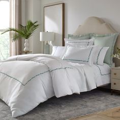 a bed with white sheets and green trimmings is shown in a bedroom setting