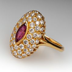 This elegant ring is centered with one (1), bezel set, marquise mixed cut natural ruby. The ruby is bordered with fifty-two (52), bead set, round brilliant cut diamonds. The ring has a reverse tapered "knife edge" style shank. The ring measures 19.5mm at the top, rises 7.7mm above the finger, tapering to 2.7mm wide and 1.6mm thick at the base of the shank. This ring is currently a size 6.75. The ring shows a lovely soft patina. Luxury Marquise Ruby Ring With Diamonds, Luxury Marquise Red Ruby Ring, Luxury Marquise Ruby Ring, Luxury Red Marquise Ruby Ring, Luxury Ruby Marquise Cut Rings, Formal Marquise Ruby Ring With Diamond, Luxury Ruby Ring Marquise Cut For Formal Events, Luxury Ruby Marquise Cut Ring For Formal Occasions, Luxury Marquise Cut Red Ruby Ring