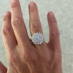 a woman's hand with a diamond ring on top of her left hand,