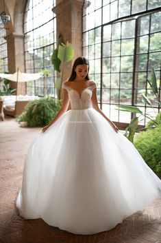 a woman in a white wedding dress posing for the camera